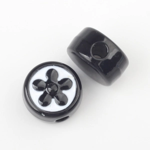 Macro detail of black enamel floral beads with white flower pattern and center hole