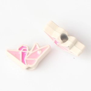 Close-up of pink and white enamel paper crane beads with side heart relief for DIY jewelry