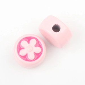 Detailed view of pink floral relief beads with central hole for DIY jewelry making