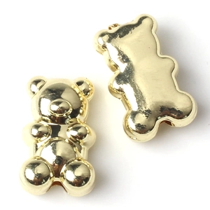 Macro shot of two high-polish golden metal teddy bear charms for DIY jewelry making