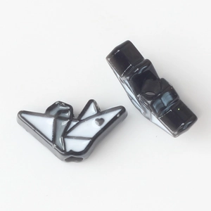Detail of origami paper crane beads with black and white enamel finish for DIY jewelry