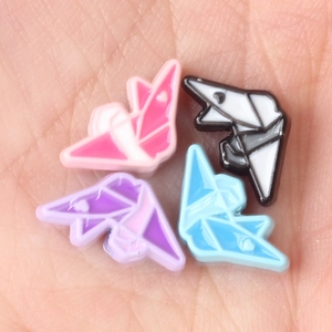 Colorful paper crane alloy beads in four colors held on palm for DIY jewelry