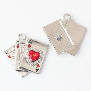 Macro view of silver playing card charms with red heart crystal and textured back