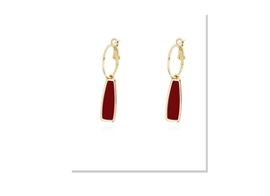 Gros plan de boucles d'oreilles dorées avec pendentifs géométriques bordeaux