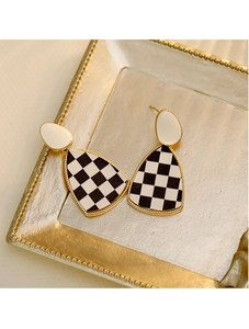 Détail macro de boucles d'oreilles en damier avec bordure dorée sur plateau