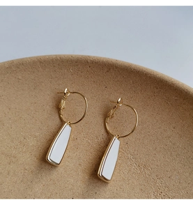 Détail de boucles d'oreilles trapèze blanches avec des bords élégants en métal doré
