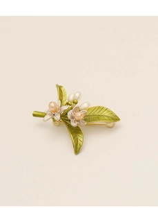 Dettaglio della spilla a fiore con placcatura in oro, perle rosa e foglie verdi
