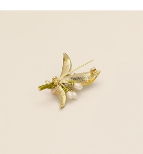 Dettaglio del retro di una spilla a fiore dorata con chiusura a spillo e perle eleganti