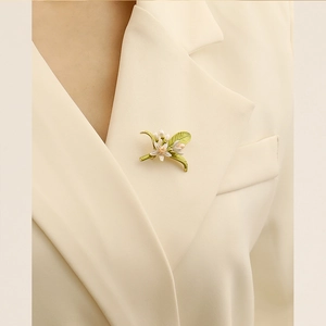 Elegante spilla a fiore con foglie verdi e perle sul risvolto di un blazer beige