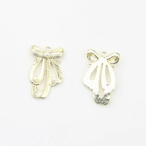 Makro-Detail von goldenen Ballettschuh-Anhängern mit Schleife und Perle für DIY-Schmuck