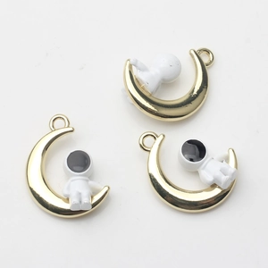 Detailansicht der goldenen Mondsichel und weißen Astronauten-Anhänger für DIY-Schmuck