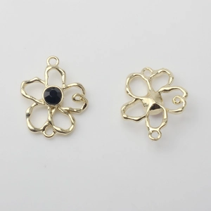 Makroaufnahme goldener hohler Blumenanhänger mit schwarzem Edelstein und Doppelringen