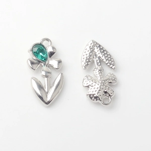 Macro detail of alloy flower pendant with green teardrop gem and textured back