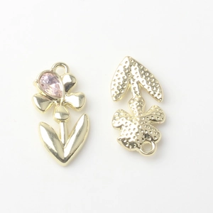 Detail of flower-shaped alloy pendants with pink teardrop stones and textured golden back