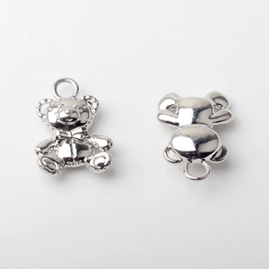 Macro detail of silver bear charm pendants showing polished front and back metal surfaces