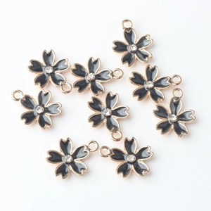 Set di dieci ciondoli a fiore di ciliegio in smalto nero con bordi dorati e piccoli strass
