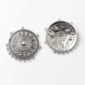 Detail of vintage round alloy connector pendants with geometric mandala sunburst patterns