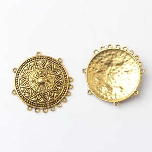 Close-up of alloy round connector pendants with sunburst pattern and hammered texture