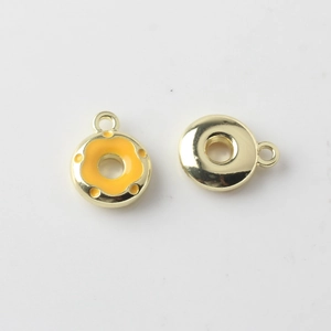 Macro detail of alloy donut charm with yellow enamel finish and golden metal backing