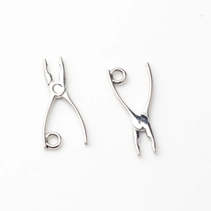 Macro detail of miniature silver alloy plier charms for DIY earring and jewelry making