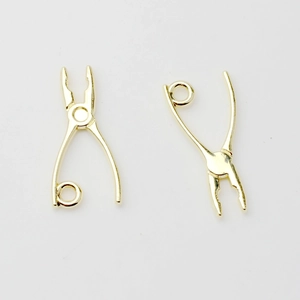 Macro detail of golden pliers-shaped alloy charms for DIY jewelry making and earring design