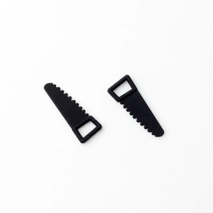 Detail of two mini black saw-shaped pendants with top loops for DIY jewelry making