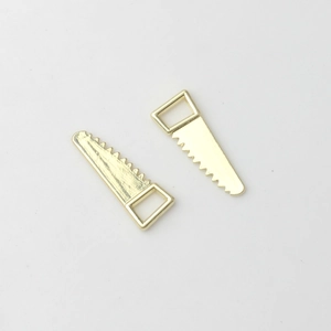 Close-up of golden alloy mini hand saw charms for creative DIY jewelry making