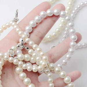 Elegante weiße Perlen-Handykette mit silbernen Karabinerverschlüssen in der Hand