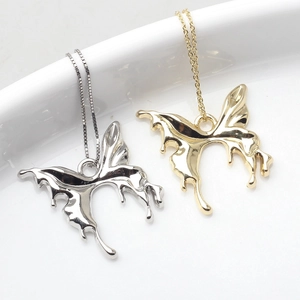 Macro detail of liquid metal butterfly pendants in polished gold and silver finishes