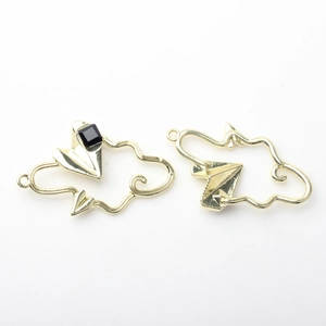 Detailed view of gold alloy cloud and paper plane pendants with a black square gem