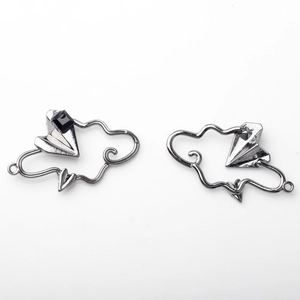Macro detail of alloy cloud and paper plane charms with black rhinestone for DIY jewelry