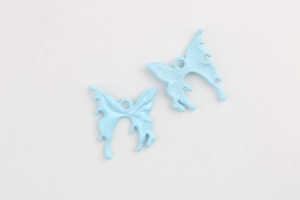 Detailed macro view of sky blue enamel butterfly charms with alloy metal texture