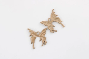 Macro detail of khaki butterfly alloy charms showing smooth front and textured back