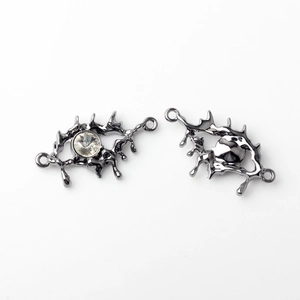 Detailed macro view of liquid metal style eye charms with white zircon and dual loops