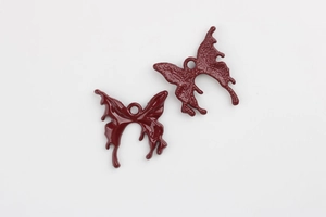 Detail of dark red butterfly alloy pendants with polished front and textured back finish