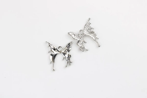 Detailed macro of silver butterfly pendants with smooth and hammered metal textures for DIY jewelry