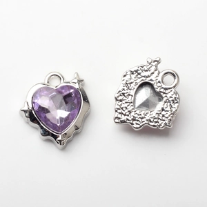 Macro detail of heart-shaped alloy pendant with purple gemstone and textured back