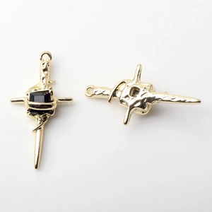 Detail of vintage golden cross pendant with textured finish and black gemstone inlay