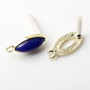 Macro detail of golden oval earring studs with blue resin inlay for DIY jewelry making