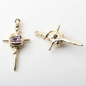 Detail of two gold-plated cross pendants with square purple zircon and textured design