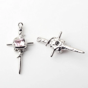 Detail of silver alloy cross sword pendants with pink gemstone and antique texture