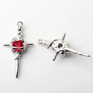 Detail showing front and back of silver gothic cross pendant with a red gemstone center