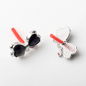 Detail of silver bow earrings with black heart stones and protective red needles