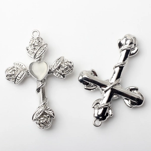 Macro detail of alloy cross pendant with heart stone and rose carvings for DIY jewelry
