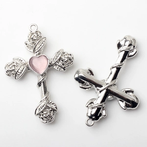 Detailed macro view of silver cross pendant with pink heart stone and rose carvings
