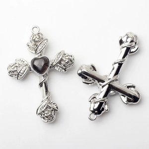 Detail of silver alloy cross pendant with rose vine and black heart-shaped stone inlay