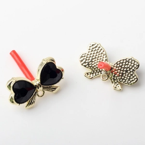 Macro view of bowknot jewelry charms with gold frames and black heart-shaped resin inlay