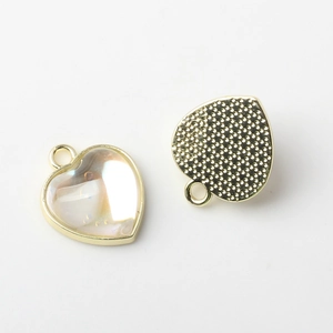 Detailed view of heart-shaped DIY jewelry pendants with pearl inlay and golden metal back
