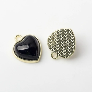 Detail of heart-shaped gold pendants with black inlay and textured metal backing