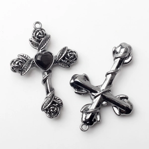 Macro detail of vintage silver cross charm with rose vine and heart-shaped black stone
